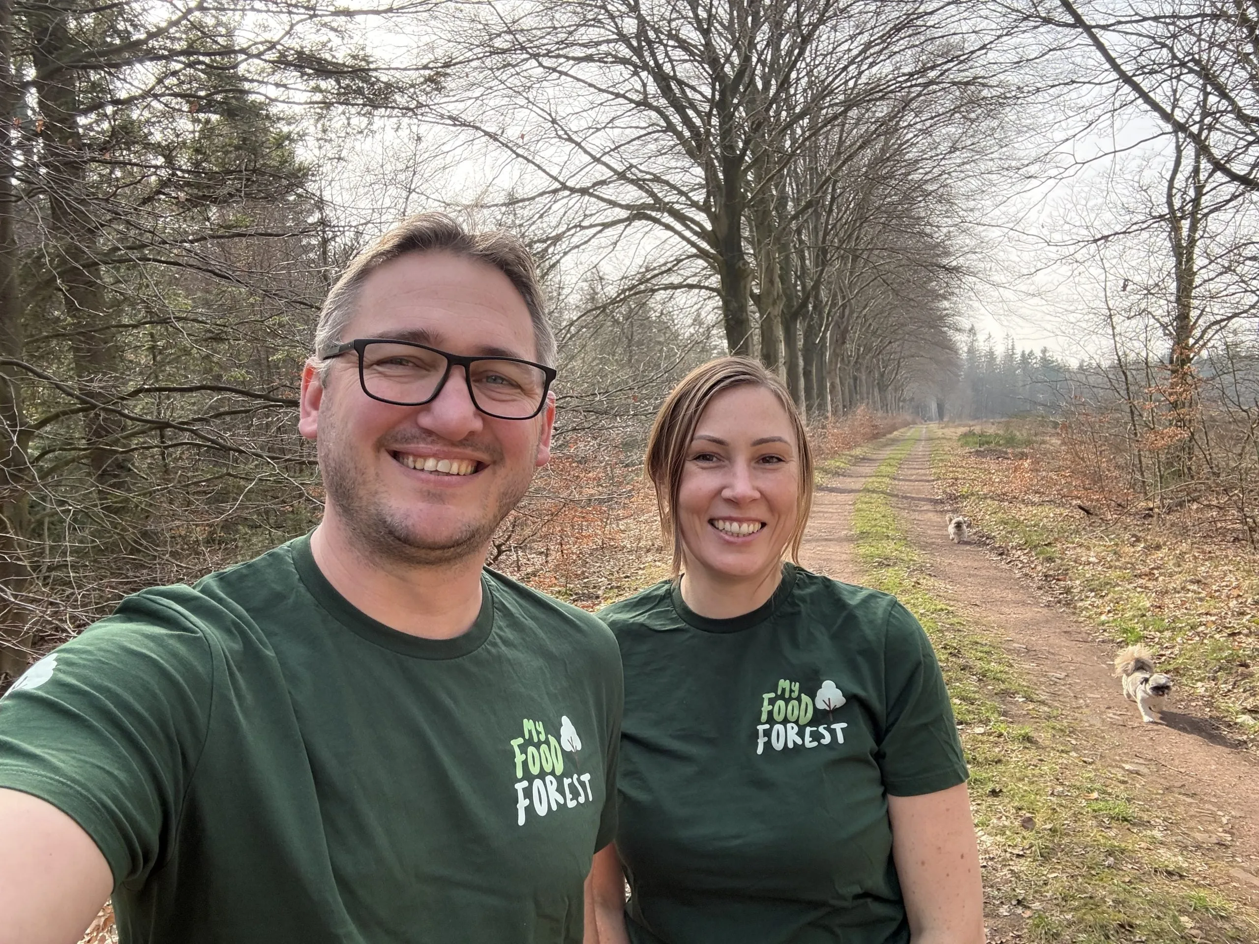 Man en vrouw in groene My Food Forest-shirts op een bospad