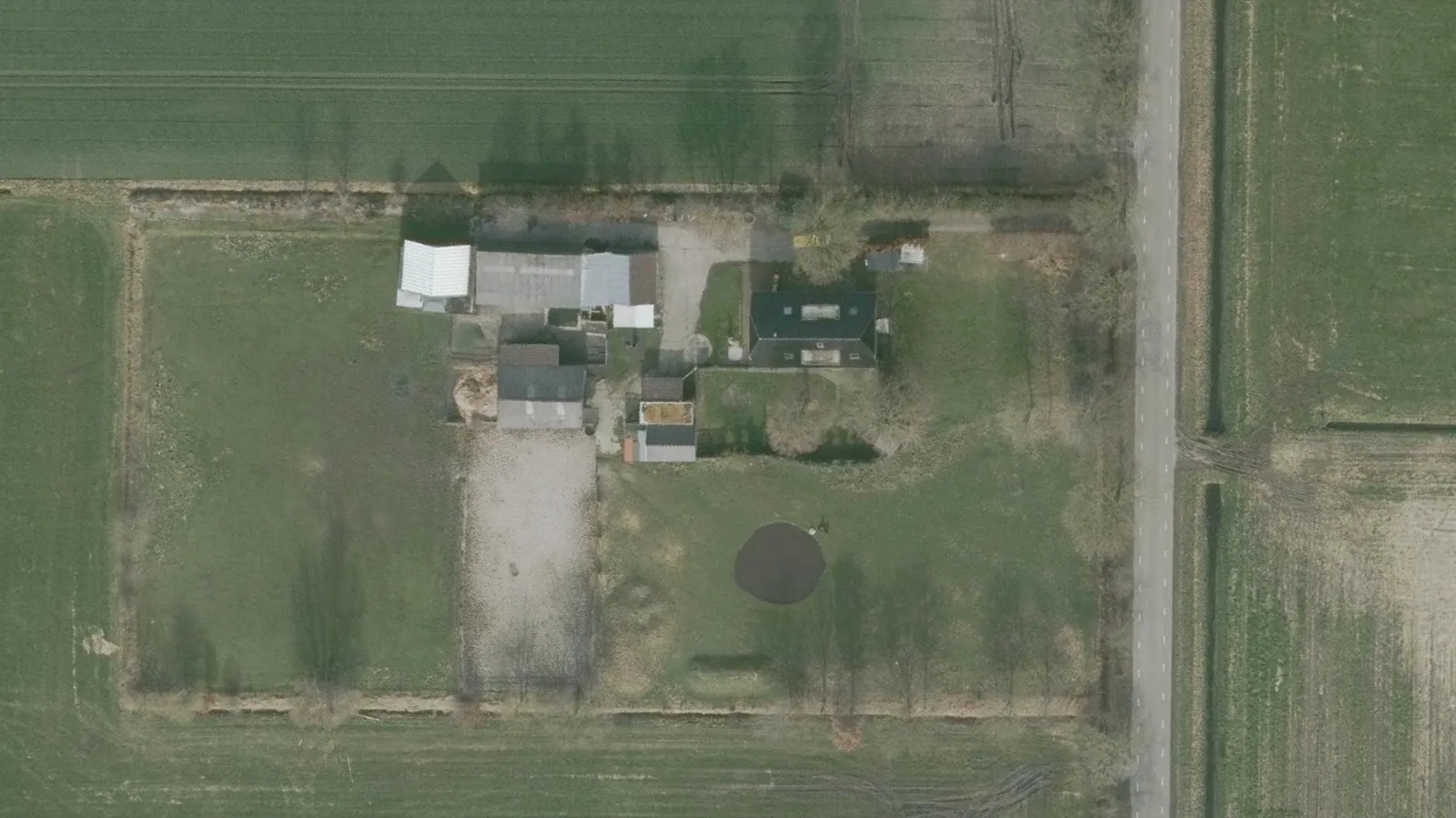 Luchtfoto van het perceel met links en rechts weiland, in het midden een zandvlakte en rechts een kleine ronde poel