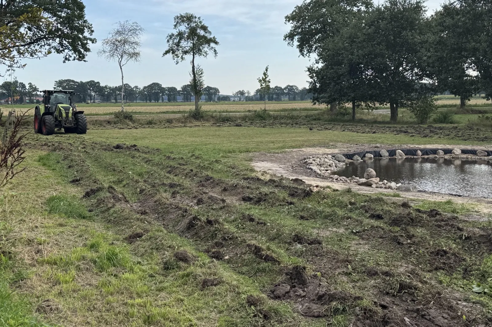 Een trekker op het land, met sporen van de woeler in het gras