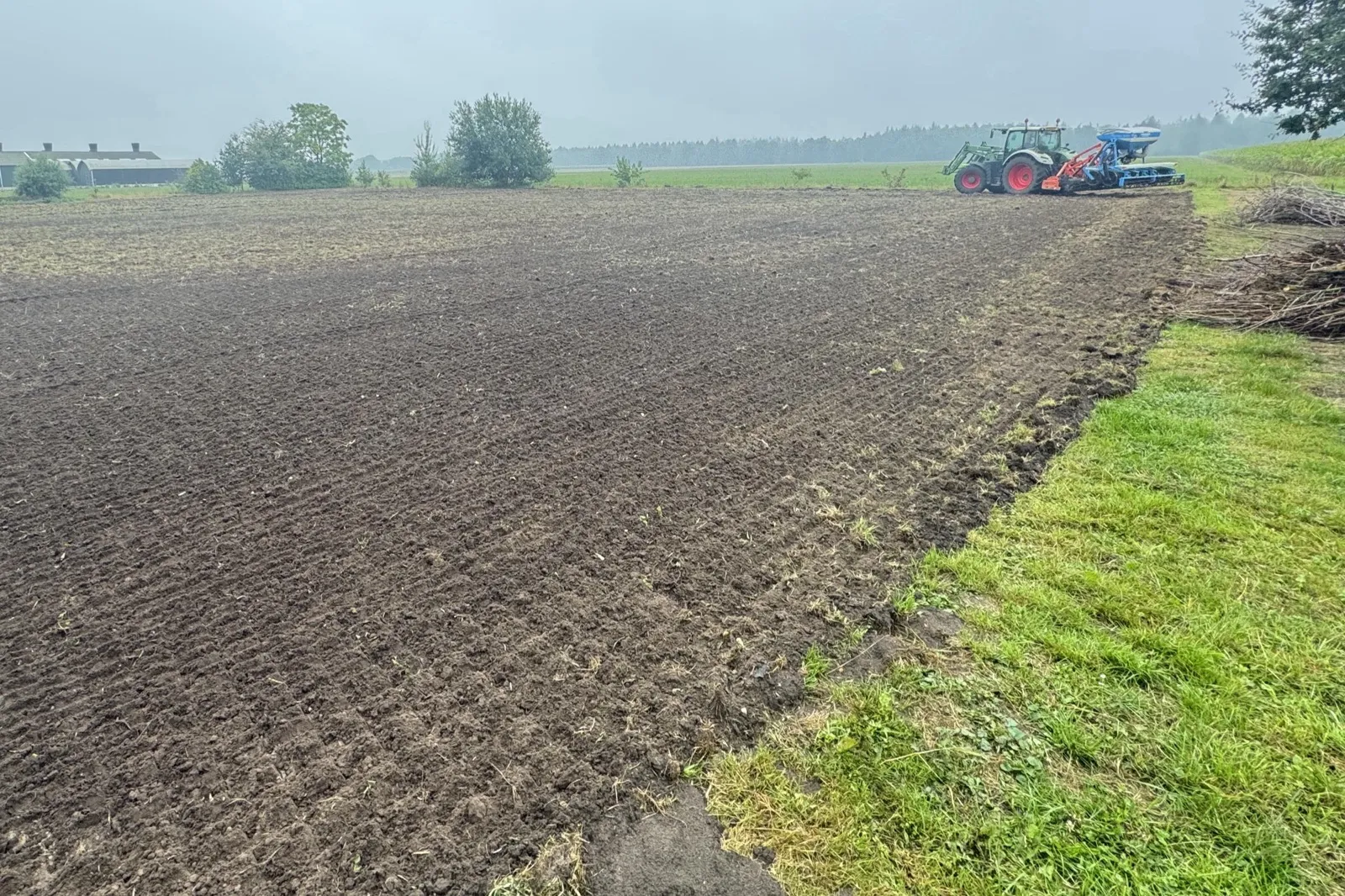 Fijne, donkere grond met achteraan een trekker met zaaimachine